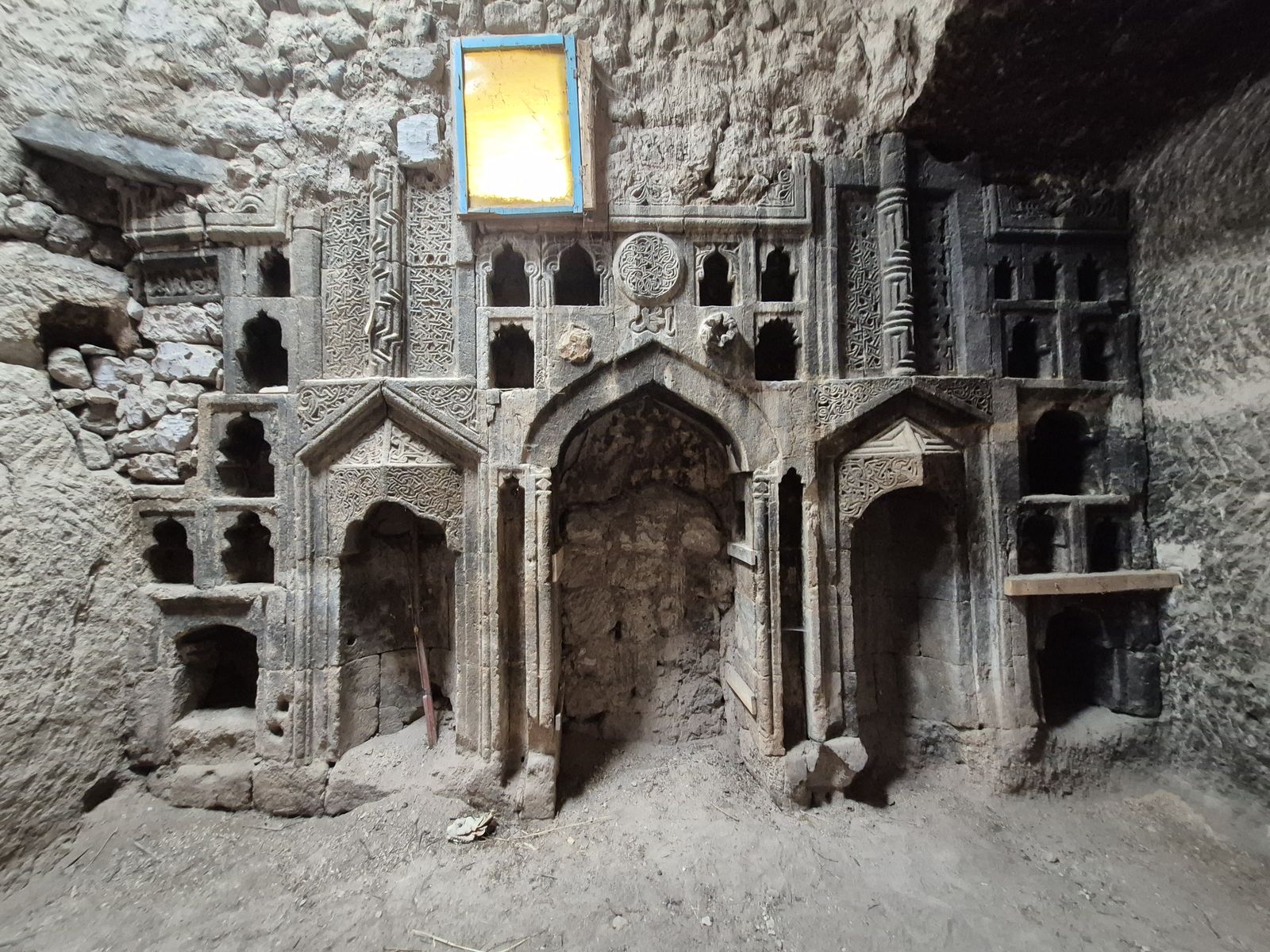 Kayaya oyulmuş cephe: ortada mihrap, iki yanında bacalı nişler.