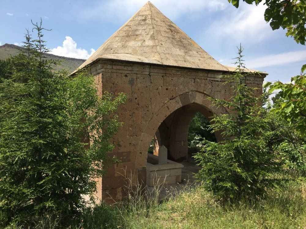 Mezarlık ortasındaki kare gövdeli türbe ve piramidal külahı.